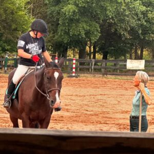 instructor talking to adult student on horse in arena