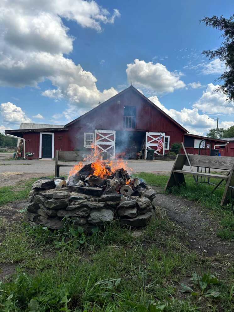 firepit with the main barn behind it under a blue sky