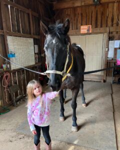 tiny student with horse in tack up area