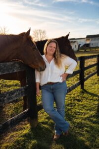 woman standing by 2 horses in a paddock